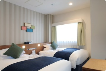 白い壁に二つのベッドが並ぶ綺麗な室内写真