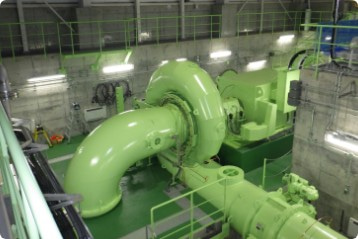 明るい緑色をした巨大なパイプで組み合わされた小水力発電設備の写真